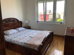 a bedroom with a bed with a wooden frame and a window at Square apartment Podgorica in Podgorica