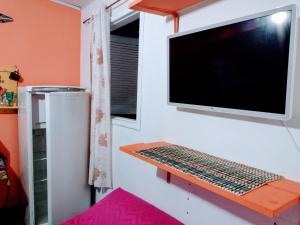 a tv on a wall with a keyboard on a shelf at Pertinho prahia toninhas in Ubatuba