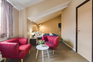 a living room with two red chairs and a table at Hotel Sky in Zadar