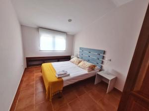Schlafzimmer mit einem Bett mit blauem Kopfteil und einem Fenster in der Unterkunft Piso Don Ramón in Razo