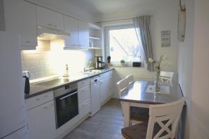 een keuken met witte kasten en een tafel en een raam bij Zur Hanse Wohnung 1 4 in Zingst