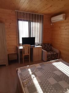 Habitación con cama, sofá y TV. en Бунгало парк Summer Life en Tyulenovo