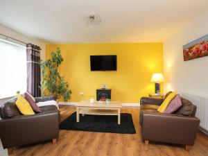 a living room with two couches and a table at Bwthyn Tyn y Coed in Bryngwran
