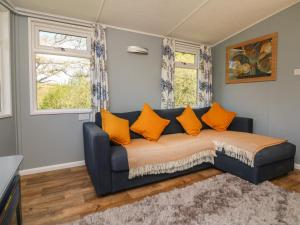 Valley Lodge في تيفرتون: أريكة زرقاء مع وسائد برتقالية في غرفة المعيشة