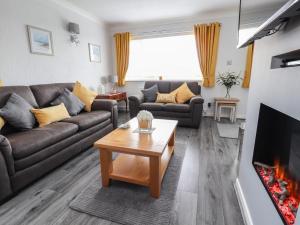 a living room with couches and a fireplace at Little Orme Bungalow in Llandudno
