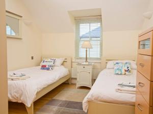 two beds in a small room with two windows at Ocean View Apartment in Thurlestone