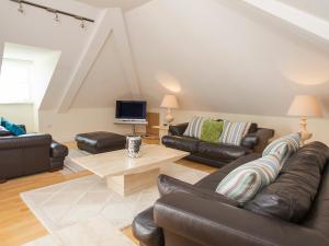 a living room with leather furniture and a tv at Ocean View Apartment in Thurlestone