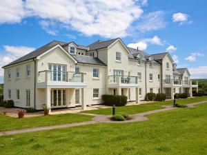 a large white house with a green lawn at Ocean View Apartment in Thurlestone