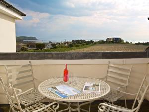 a table and chairs on a balcony with a view of the ocean at Ocean View Apartment in Thurlestone
