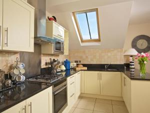 a kitchen with white cabinets and black counter tops at Ocean View Apartment in Thurlestone