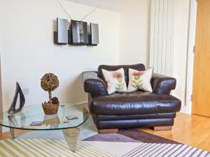 a living room with a leather couch and a glass table at Ocean View Apartment in Thurlestone