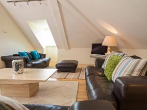 a living room with leather furniture and a tv at Ocean View Apartment in Thurlestone