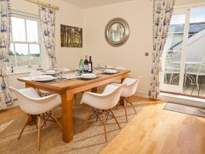 a dining room with a wooden table and white chairs at Ocean View Apartment in Thurlestone