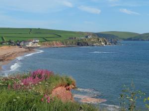 a view of a body of water with pink flowers at Ocean View Apartment in Thurlestone