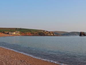 a beach with a body of water and a rocky shore at Ocean View Apartment in Thurlestone