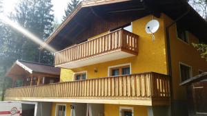 a yellow house with a balcony and a satellite at Appartements Kirchgasser Untertauern in Untertauern