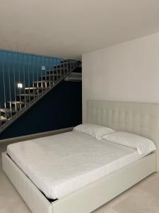 ein weißes Bett in einem Zimmer mit einer Treppe in der Unterkunft Morin Forte dei Marmi in Forte dei Marmi