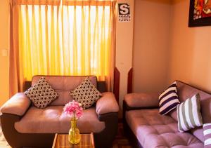 una sala de estar con 2 sofás de cuero y una mesa. en Hostal Casa Del Inka, en Cusco
