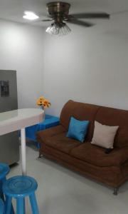 sala de estar con sofá marrón y 2 almohadas azules en Divijuka en Taganga