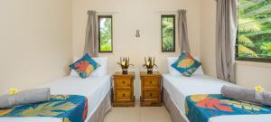 a room with two beds and two windows at Cook Islands Holiday Villas - Turangi Lagoon in Muri