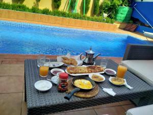 a breakfast table with food and drinks on a table by a pool at Fancy house in Oualidia