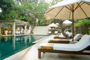 a swimming pool with chairs and umbrellas next to a resort at Komaneka at Monkey Forest Ubud in Ubud