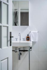a white bathroom with a sink and a mirror at Bondi Beach House in Sydney +29 photos