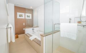 ホノルルにあるKaimana Beach Hotelのバスルーム(洗面台、ガラス張りのシャワー付)