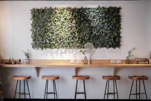 a bar with stools in front of a green wall at Luke 27 Homestay in Tainan