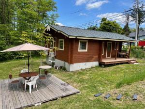 een klein huis met een tafel en stoelen en een parasol bij Haramura CAFE Lodge - Vacation STAY 33104v in Hara