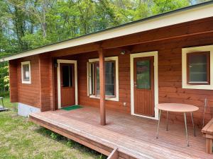 eine hölzerne Veranda einer Hütte mit einem Tisch und einem Stuhl in der Unterkunft Haramura CAFE Lodge - Vacation STAY 33104v in Hara