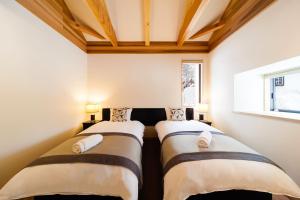 two beds in a small room with a ceiling at Asagiri Chalet Hakuba in Hakuba