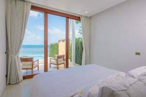 a bedroom with a bed and a view of the ocean at White Whale Beachfront Pool Villa in Ban Bang Po