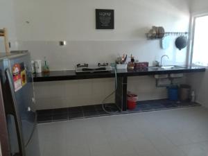 eine Küche mit einer Theke, einer Spüle und einem Kühlschrank in der Unterkunft Maryam Kiara 2 in Kertih