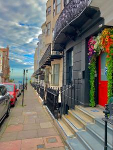 Brighton Black Hotel & Hot Tubs في برايتون أند هوف: رصيف بجانب مبنى عليه زهور