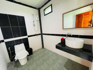 a bathroom with a toilet and a sink and a mirror at Phurin Thara Resort in Ko Lanta