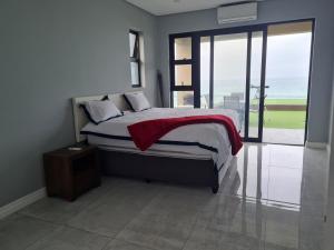 a bedroom with a bed with a view of the ocean at Qophelo Sea Views in La Mercy