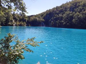 a blue lake with a waterfall in the background at Apartment Ivan & Iva in Gornji Vaganac