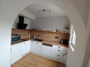 a kitchen with white cabinets and an archway at Apartmán Lenka in Boršice