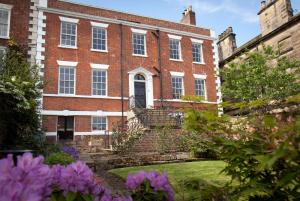 a large brick building with stairs and purple flowers at Thistlebank Townhouse in Whitby
