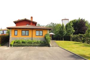 a yellow house with a driveway in front of it at Apartamentos Rurales Senda Costera in Hontoria