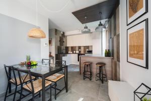 a dining room and kitchen with a glass table and stools at Mary&Arte Apartments Browar Lubicz in Krakow