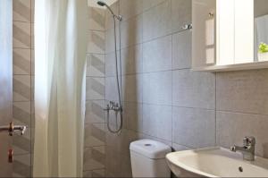 a bathroom with a shower and a toilet and a sink at Limnonari Beach Rooms in Skopelos Town