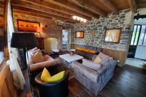 a living room with couches and a stone wall at Maison Jeanne (proche Bécherel pour 14 personnes) in Saint-Pern