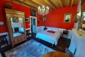 a bedroom with red walls and a bed and a mirror at Maison Jeanne (proche Bécherel pour 14 personnes) in Saint-Pern