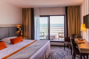 a hotel room with a bed and a desk and a balcony at Atlantic Hôtel & Spa in Les Sables-d'Olonne