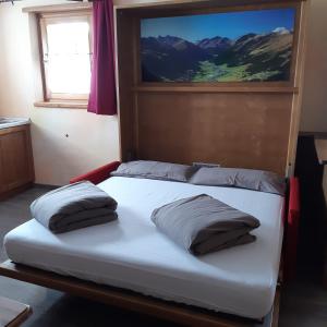 a bed with two pillows on it in a room at Bait DossAlt in Livigno