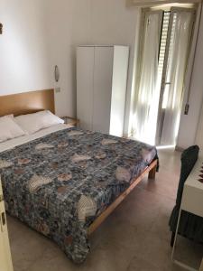 ein Schlafzimmer mit einem Bett mit einer Decke darauf in der Unterkunft La veranda in Ardea