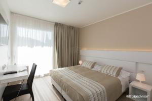 um quarto com uma cama, uma secretária e uma janela em Hotel Villa Katy em Bardolino