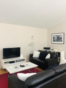 邓斯伯勒Cape Villas 23的客厅里有一张黑色沙发和一台电视